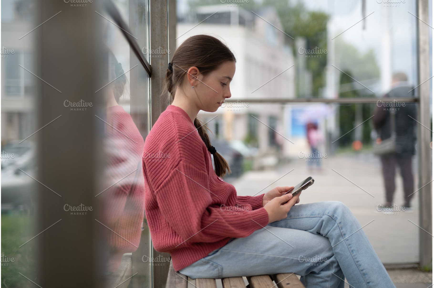 Young girl sitting at bus stop, a Person Photo by HalfPoint