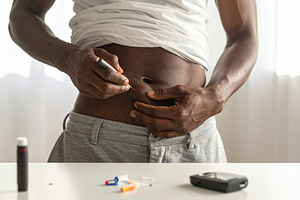 Adult person injecting insulin in the abdomen with a pen, a Person Photo by DanFLCreativo