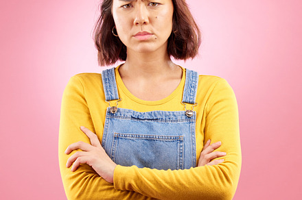 Portrait, frown and angry asian woman with arms crossed in studio and defensive body language on pink background. Wtf, face and frustrated Japanese female disappointed by news, fail or mood isolated, a Photo by Peopleimages.com