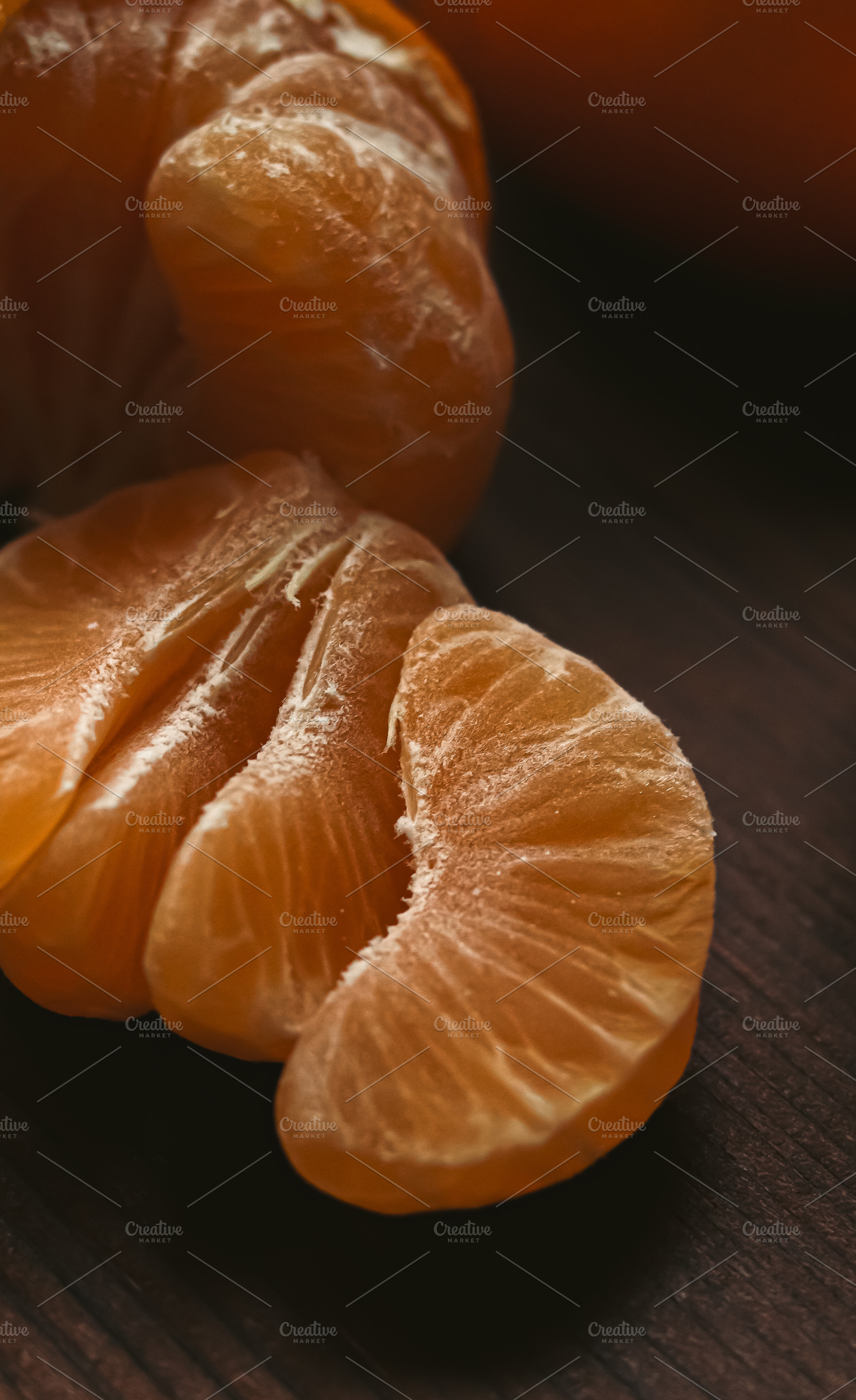 Tangerine fruit segments freshly peeled on a dark wooden table, highlighting he, a Photo by Studio ANNA