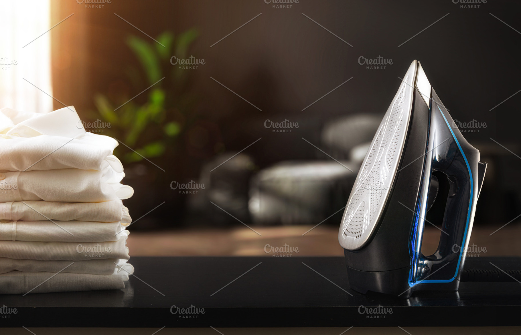 Iron on black living room table with white shirts stacked, a Technology Photo by Davizro's Market