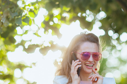 happy woman in dress and jacket in city using smartphone, a Person Photo by Alliance Images