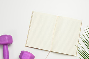 Open lined notebook with blank pages, surrounded by purple dumbb, a Sports & Recreation Photo by ndanko