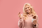 I love cocolate. Pretty lady holding chocolate bar and smiling at camera, stand, a Photo by Prostock-Studio (Thumbnail 1 of 2)