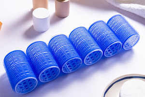 Set of Blue Plastic Hair Rollers with Hair Care Products on Whit, a Business Photo by MDBildes