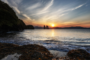 Colorful sunset over rocks in ocean, a Nature Photo by Alexander-Piragis