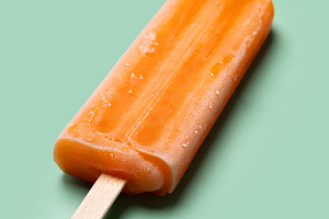 Orange popsicle on green background, a Food & Drink Photo by etorres69
