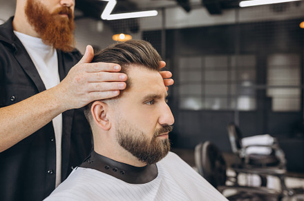 Stylish man getting haircut at the barbershop. Professional barber at work proc, a Person Photo by Volodymyr Melnyk