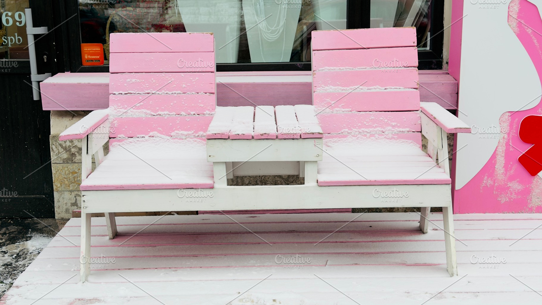 A pink and white outdoor bench covered in snow, situated in front of a shop win, an Industrial Photo by Textures & Backgrounds