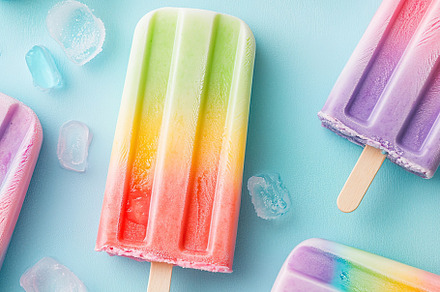 Colorful rainbow ice cream arranged on a light blue background with ice cubes, a Food & Drink Photo by AlyaAnd
