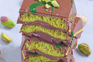 Stack of pistachio Dubai style chocolate bars with whole pistachios showing fil, a Food & Drink Photo by iuliia_n