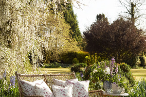 Wicker sofa and coffee table with floral cushions providing a se, a Photo by Studio ANNA