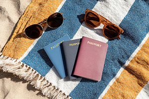 Colorful passports and sunglasses displayed on a beach towel under the sun, a Photo by AlyaAnd