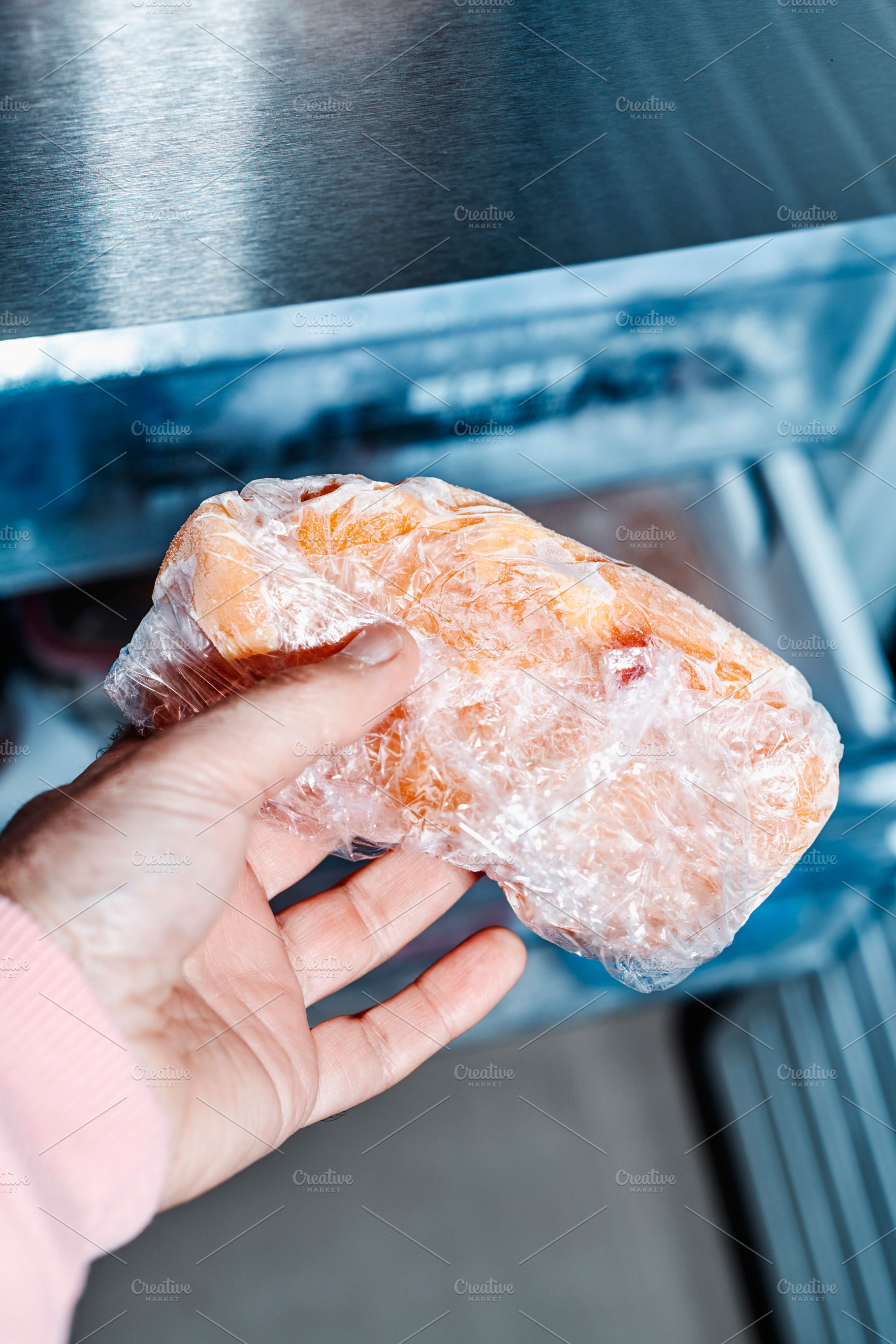 a man grips frozen chicken from the freezer, a Photo by Nito