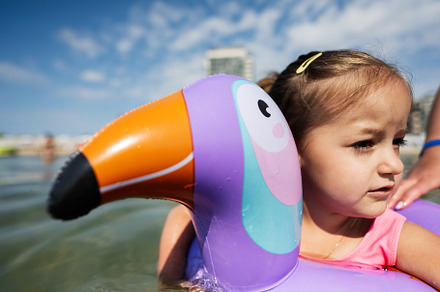 Little girl swimming in the sea with inflatable ring like toucan, a Person Photo by AS photostudio
