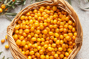 Fresh sea buckthorn berries overflowing a small wicker basket, a Food & Drink Photo by Olena Rudo