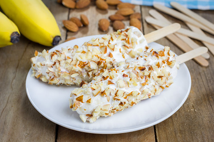 Frozen banana covered with yogurt and almonds, a Food & Drink Photo by iuliia_n