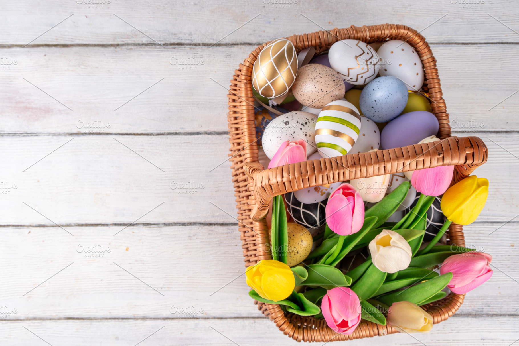 Easter eggs and tulips flowers in basket on wooden background, a Holiday Photo by Rimma
