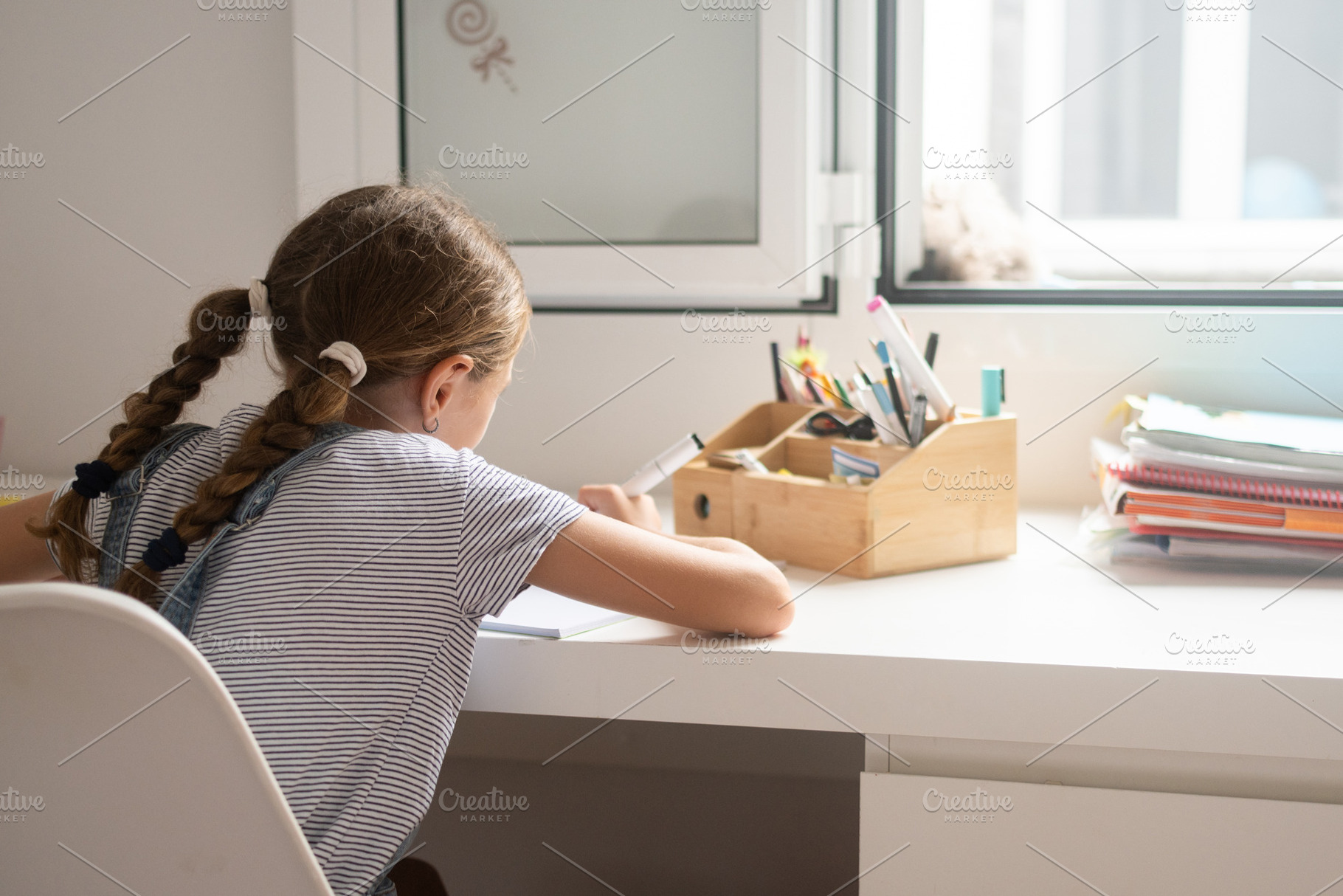 Young girl studying and writing homework at desk at home, a Photo by etorres69