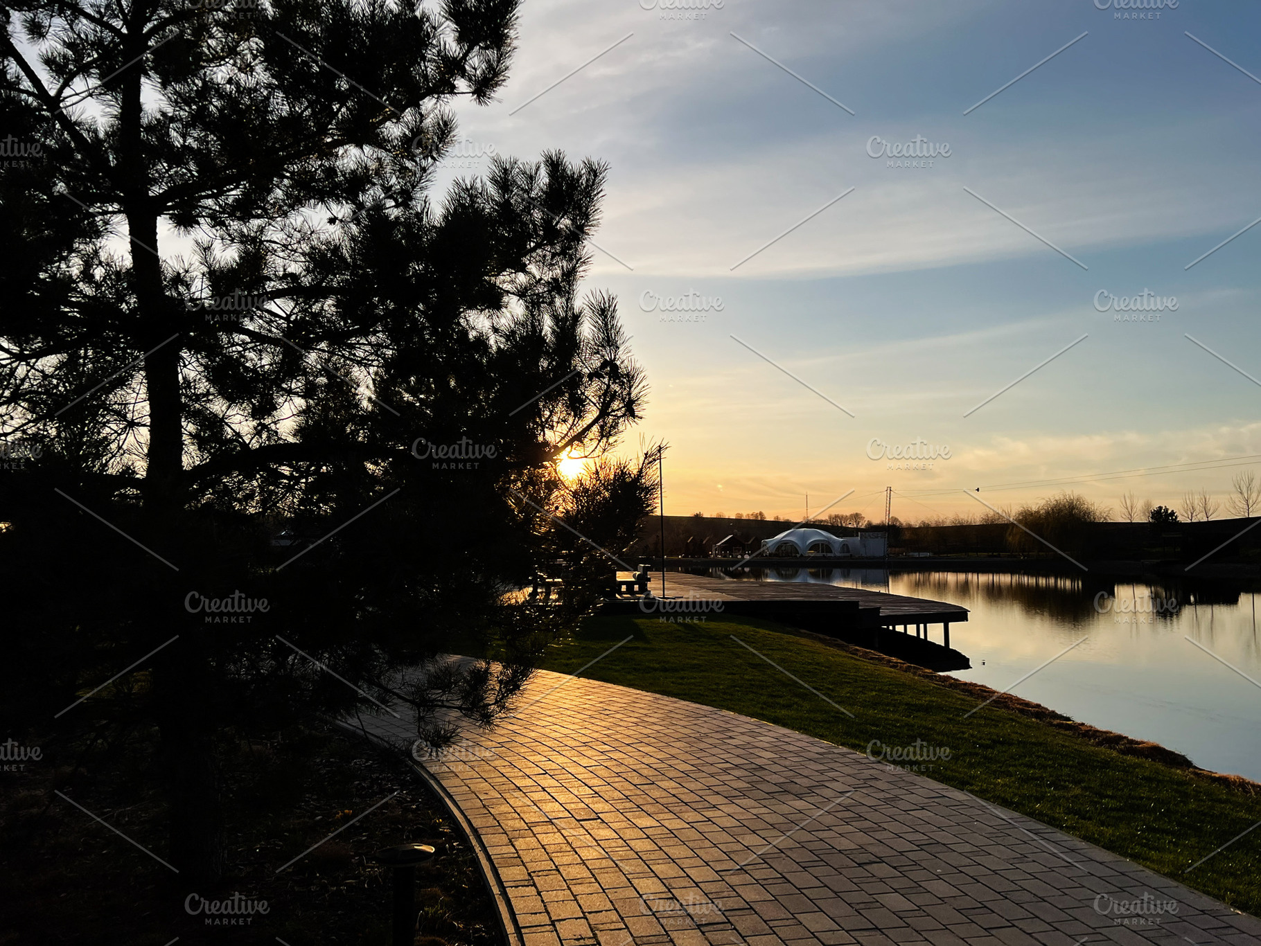 Peaceful riverside path at sunset with view of serene nature and trees, a Photo by AS photostudio