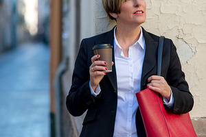 Businesswoman with coffee standing in city street, a Photo by RF Images