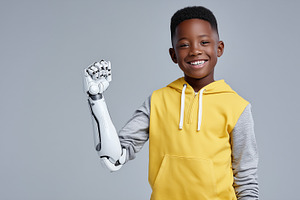 Happy black boy with robotic arm, a Health & Medical Photo by MistyDay