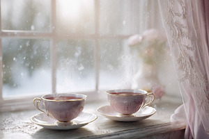 Two steaming tea cups on a window sill with falling snow, creati, a Photo by Studio ANNA