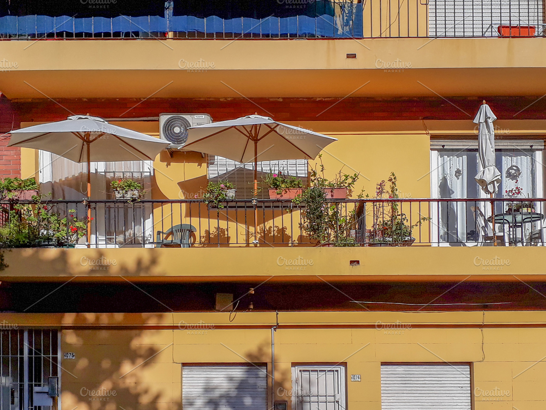 Residential building balcony with umbrellas and plants, an Architecture Photo by DanFLCreativo