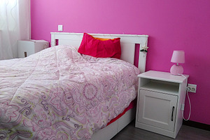Cozy bedroom with pink wall and floral bed, an Architecture Photo by DanFLCreativo