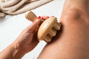 Hand holding a wooden massage roller during maderotherapy on the, a Beauty & Fashion Photo by MDBildes