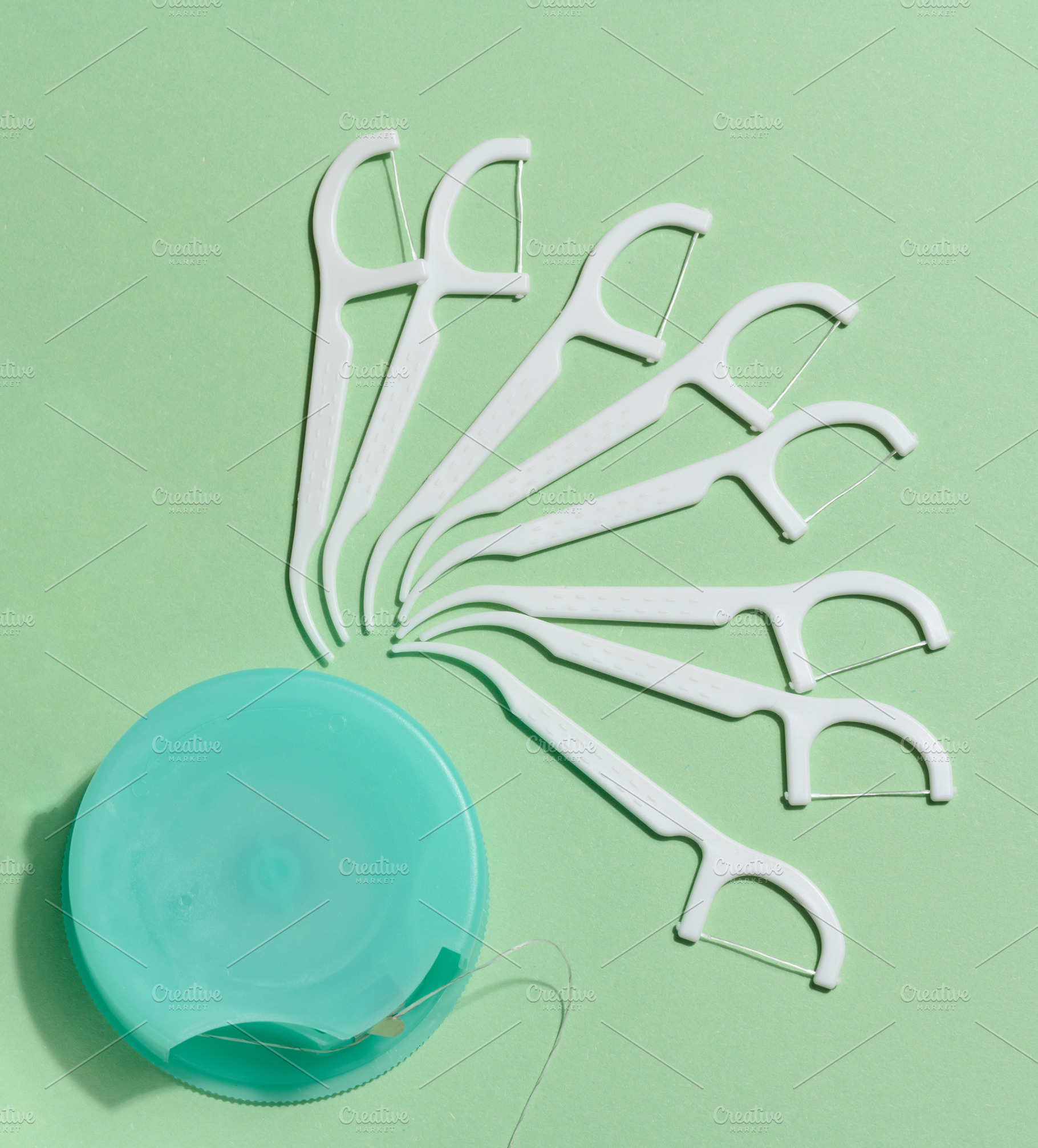 A flat lay composition of white dental floss picks fanned out ar, a Health & Medical Photo by ndanko