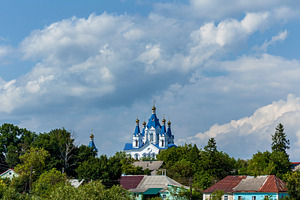 Blue domed orthodox church rising above green village, an Architecture Photo by Photostock