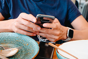 a man checks a charging phone at the table, a Photo by Nito