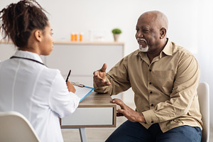 Black patient talking to doctor during appointment, a Photo by Prostock-Studio