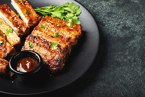 Hot grilled spare ribs from a summer BBQ served on a plate with sauce. Top view, a Food & Drink Photo by Budarinphoto