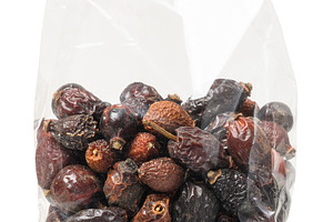 Transparent plastic bag filled with dried rose hips, isolated ba