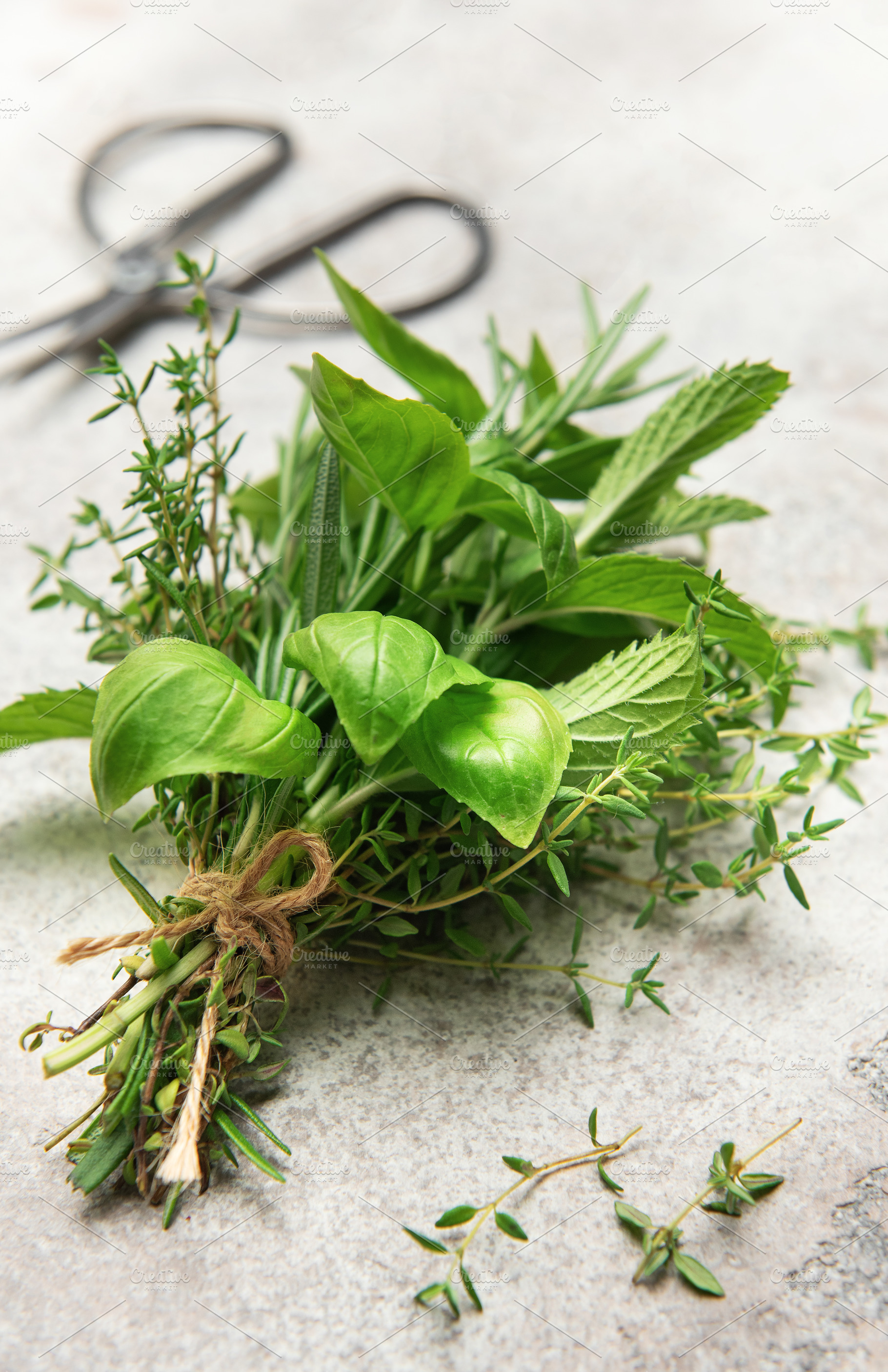 Fresh herbs tied together with twine on gray table with scissors, a Food & Drink Photo by Olena Rudo