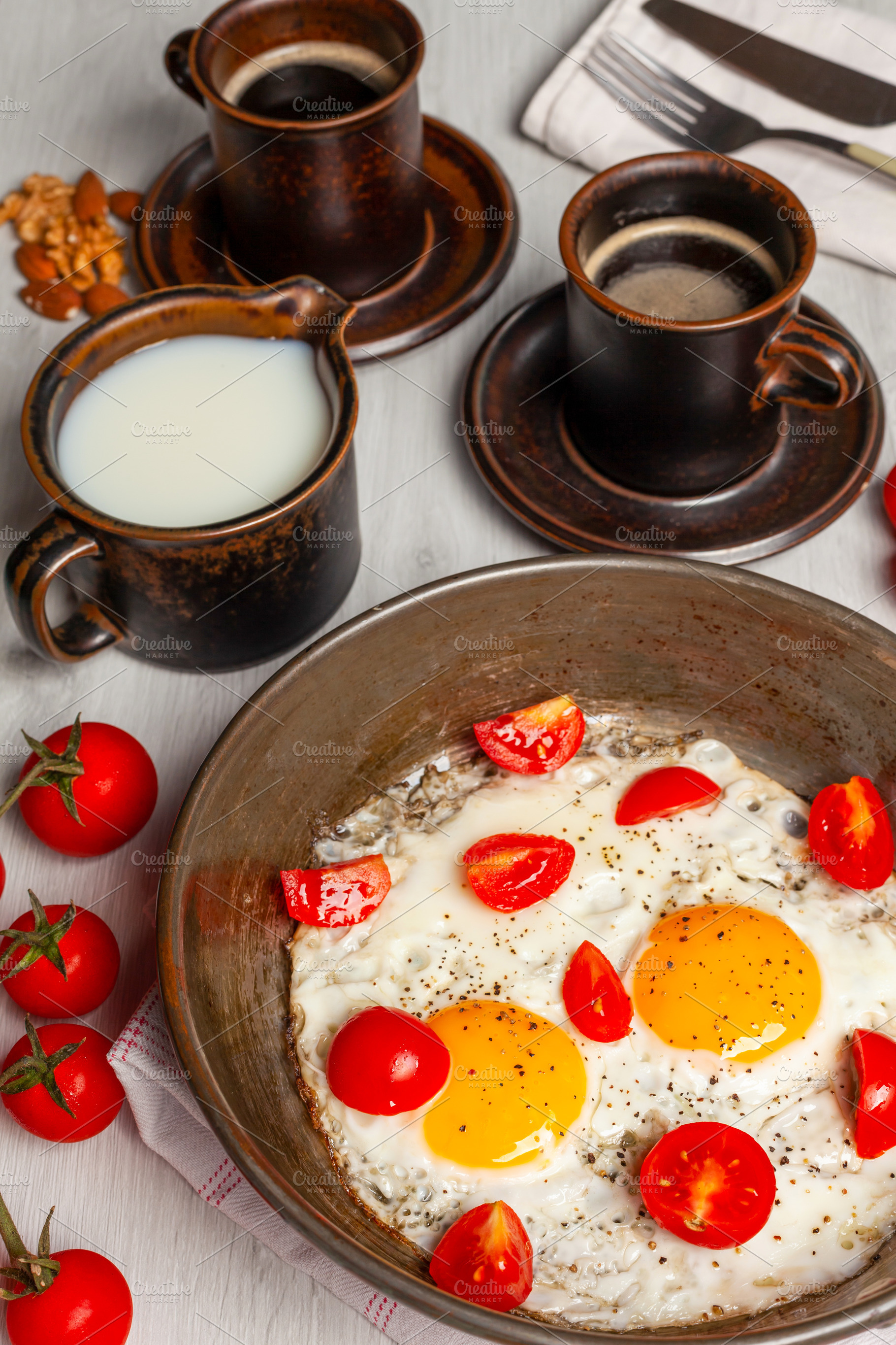 Delicious breakfast with fried eggs and cherry tomatoes in a pan, a Food & Drink Photo by Antonio Gravante Market