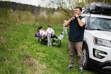 Man in sleeveless vest against suv car with roof rack box, famil, a Person Photo by AS photostudio