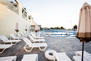 Outdoor swimming pool with white loungers and umbrellas during daytime, a Photo by AS photostudio
