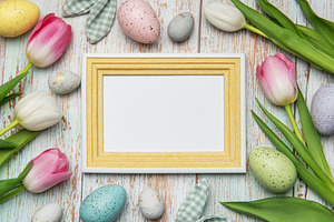 Easter eggs and tulips framing blank picture frame on wooden bac, a Holiday Photo by Olena Rudo