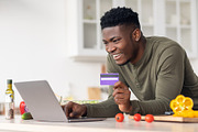 Ordering Food Online. Black Guy Using Laptop And Credit Card In Kitchen, a Photo by Prostock-Studio (Thumbnail 2 of 2)