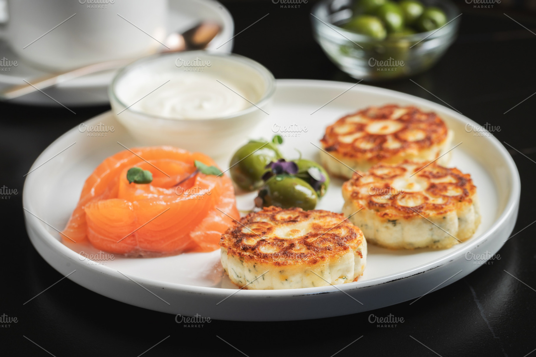 Savory Syrniki with Smoked Salmon, Olives and Sour Cream on White Plate, a Food & Drink Photo by Budarinphoto
