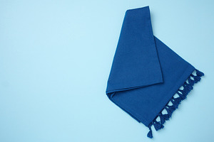 Folded blue kitchen towel on a blue background, top view. Copy s, a Food & Drink Photo by ndanko