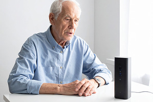 Elderly person speaking near a voice-generating device, a Person Photo by DanFLCreativo