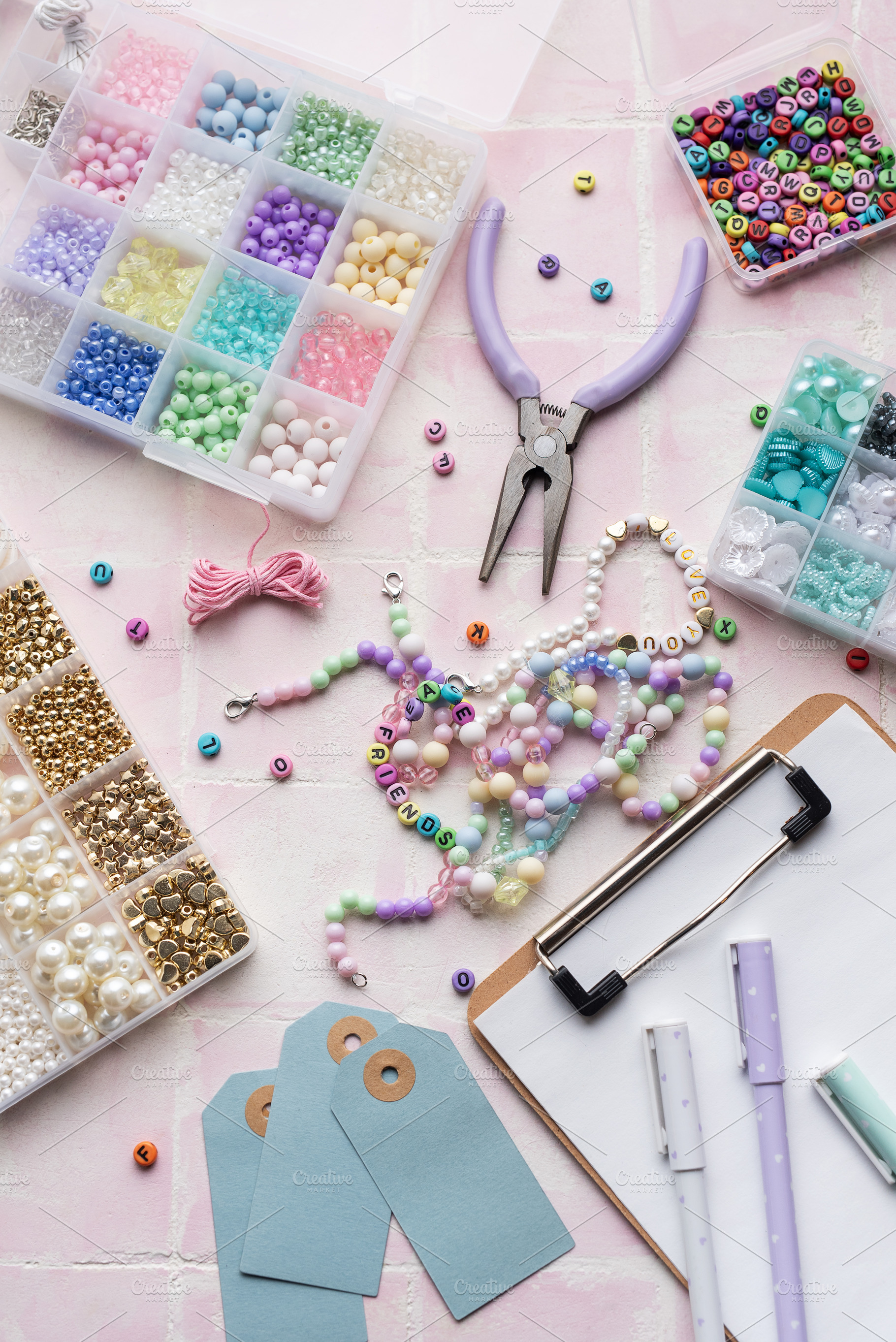 Colorful beads and jewelry making supplies arranged on pink tile, an Arts & Entertainment Photo by Olena Rudo