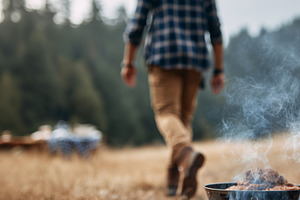 Man grilling meat over campfire in, a Person Photo by MistyDay