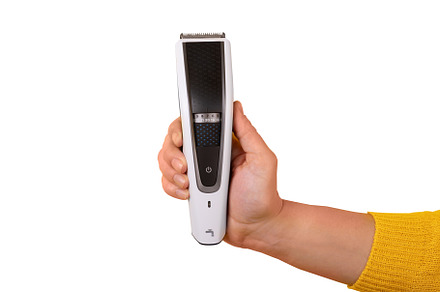 Close-up of a hand in yellow sleeve holding a modern electric be