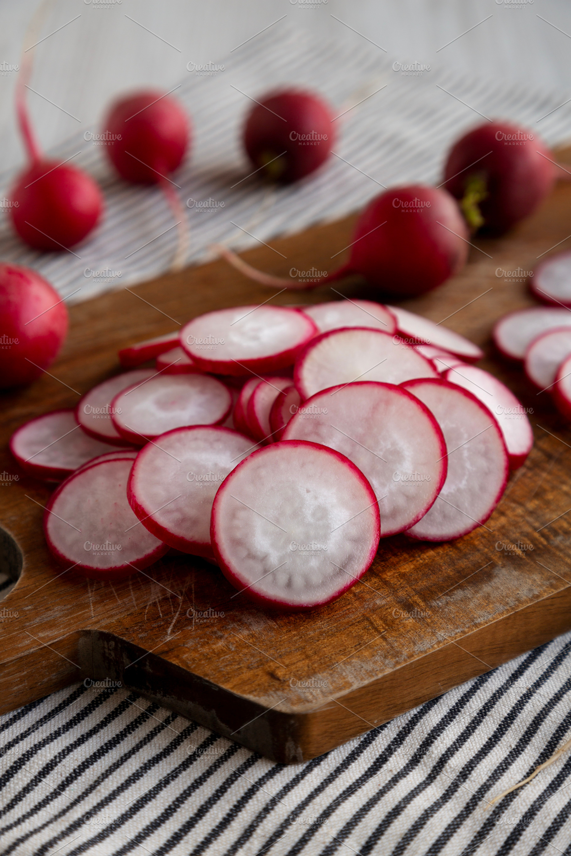 Raw Red Radish Slices on a Cutting Board, side view., a Food & Drink Photo by LiudmylaChuhunova