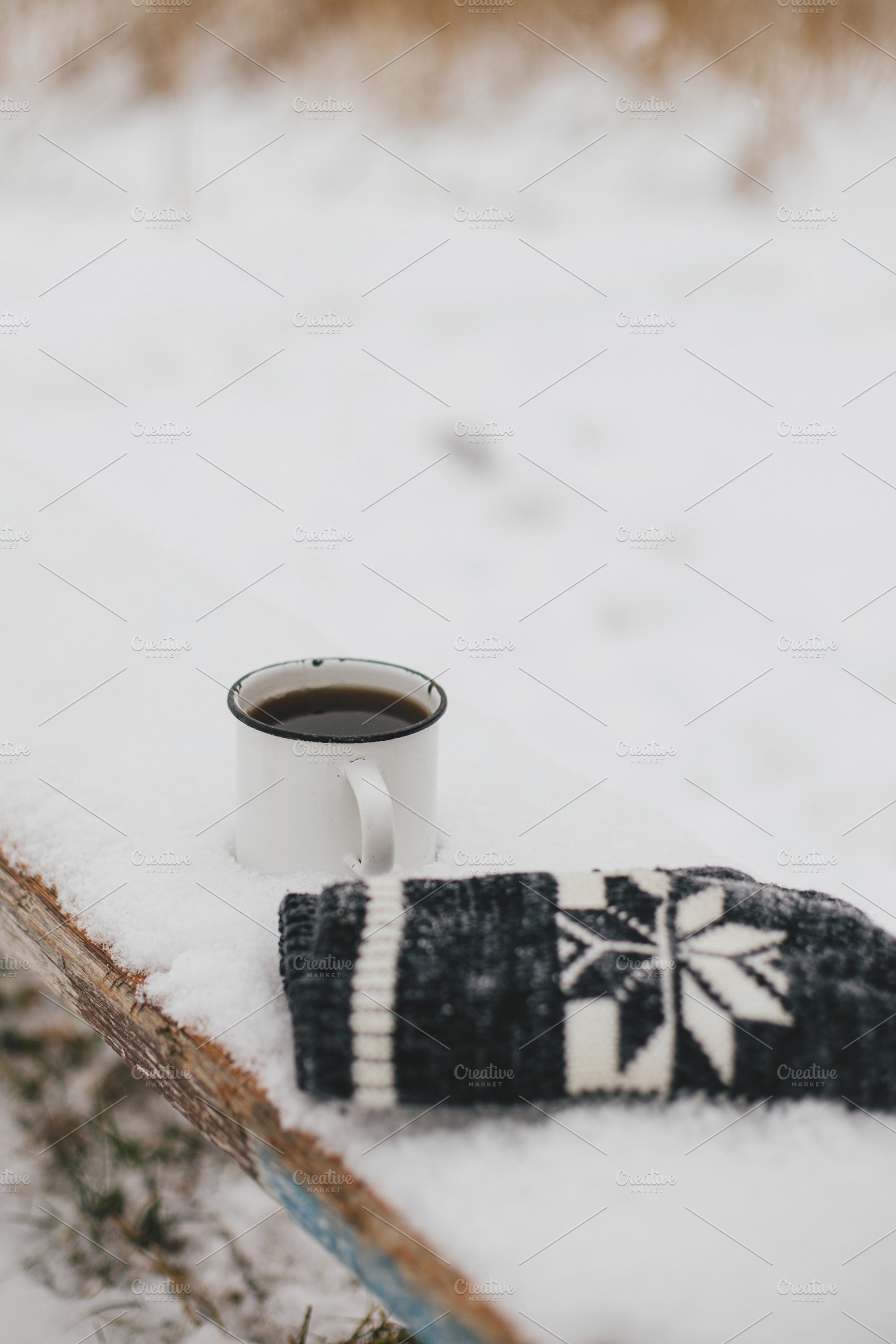 Warm cup of tea and cozy knitted gloves in snow on wooden bench, a Holiday Photo by Sonjachni